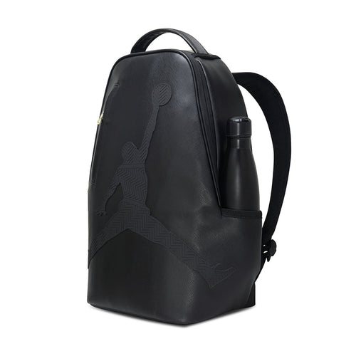 Black backpack with side pocket and attached water bottle, gold zipper detail