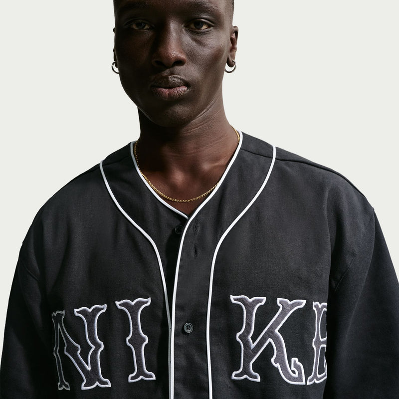 Men's black baseball top close-up with white trim and 'NI' 'KE' lettering